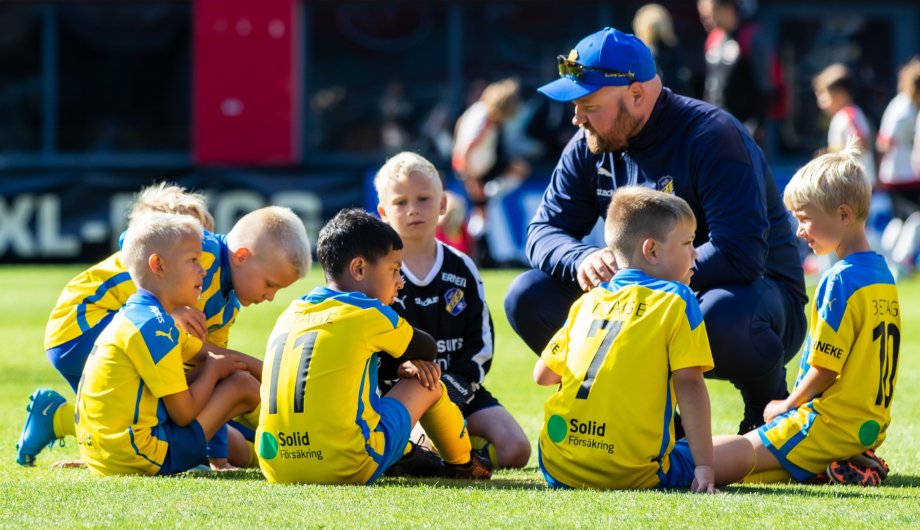 Unga fotbollsspelare samlade runt sin tränare
