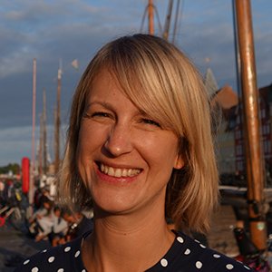 Porträtt på leende kvinna som står i en hamn i kvällssol