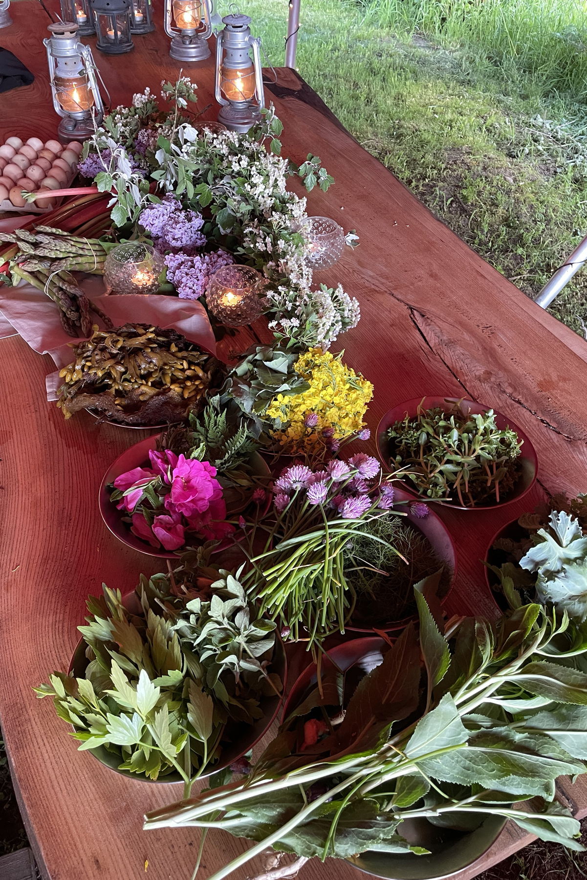 Bord utomhus fyllt med blommor och ätliga växter.