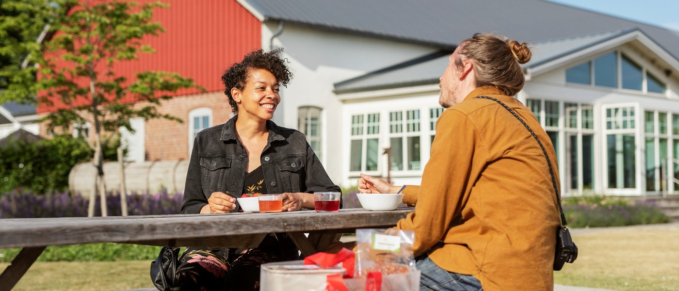 Två personer fikar utomhus. Foto.