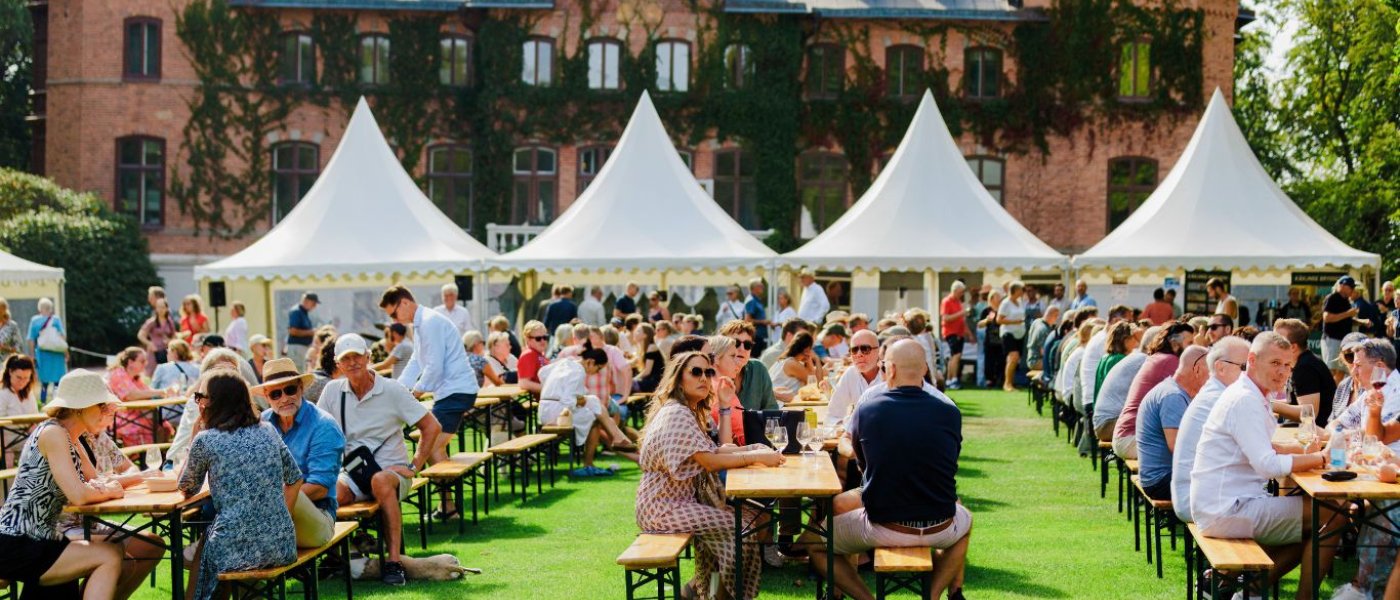 Massa ätande och drickande folk på Skåne Food Fest med Sofieros slott i bakgrunden