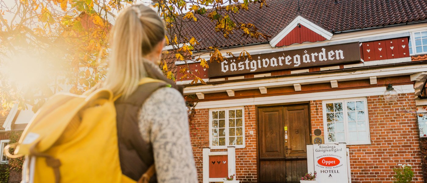 En vandrare i motljus på väg till en gästgivaregård. Foto.