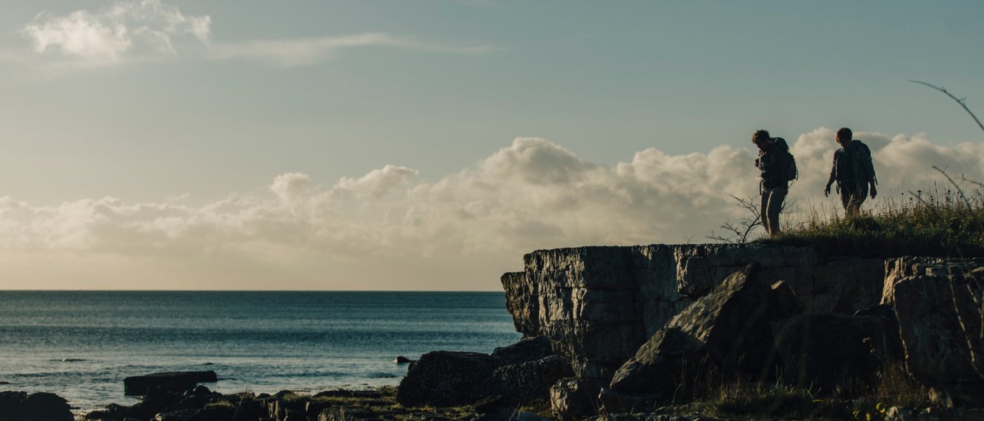Två kvinnor står på en klippa och tittar ut över havet