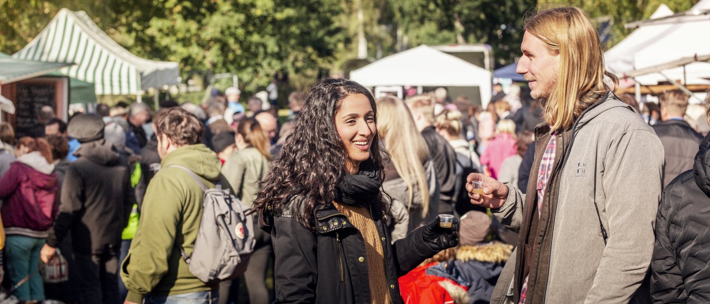 Ett par står i förgrunden till en skördemarknad