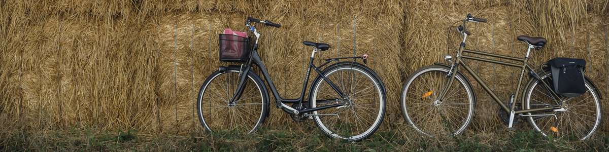 Två cyklar står lutade mot en höbal. Foto.