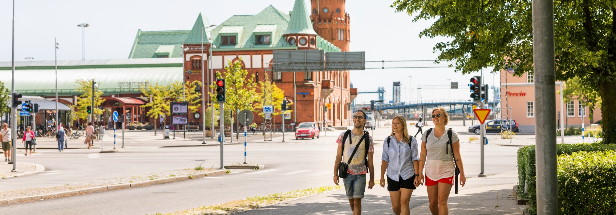 Tre personer promenerar i grönskande stad