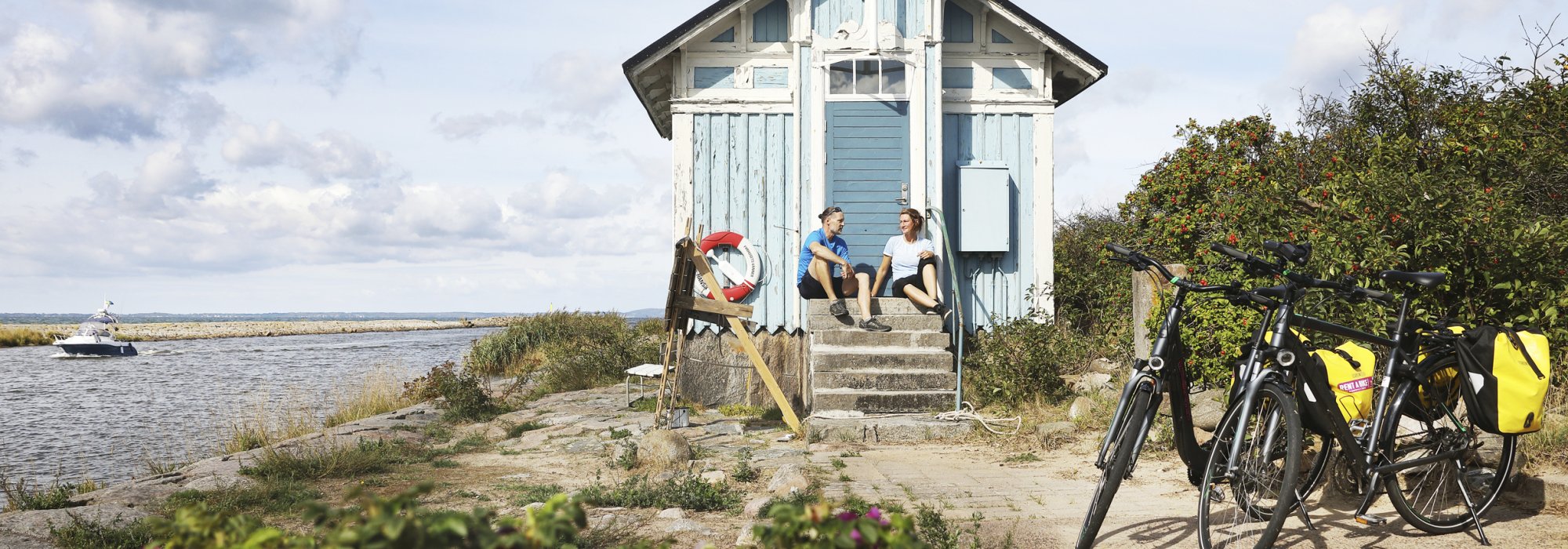 Två cyklister pausar vid en stuga vid vattnet