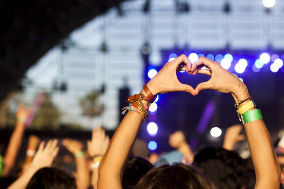 Person i publik på koncert gör ett hjärta med händerna