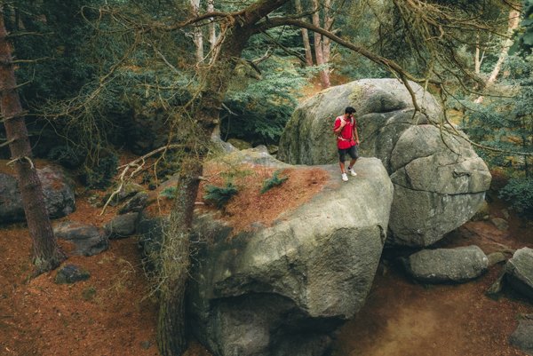 En man klättrar på stora stenar i skogen