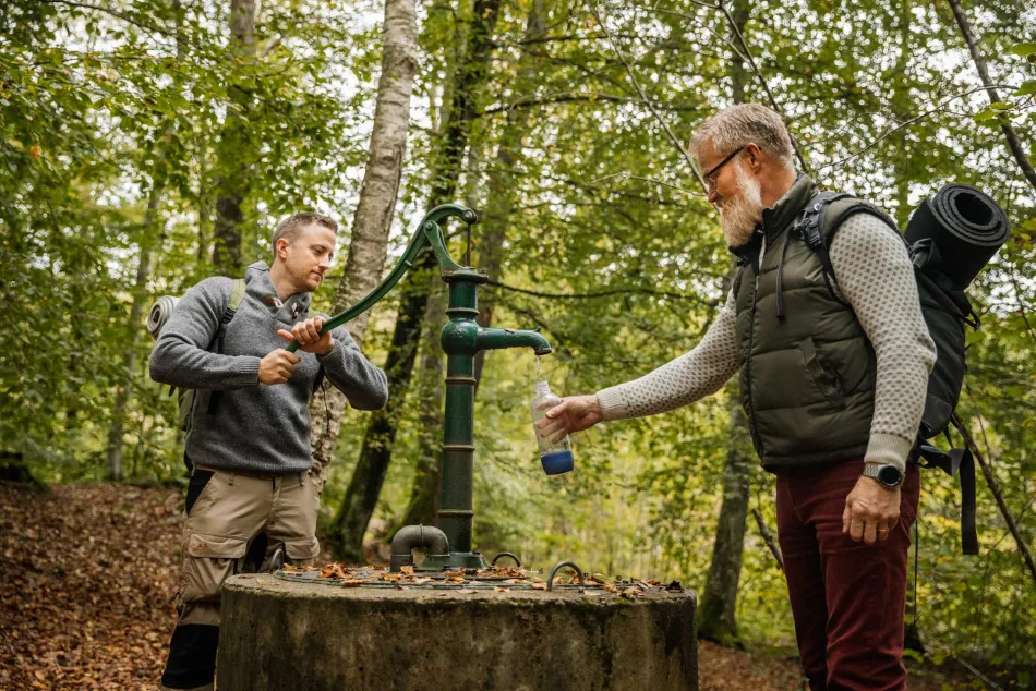 Två män pumpar vatten i skogen