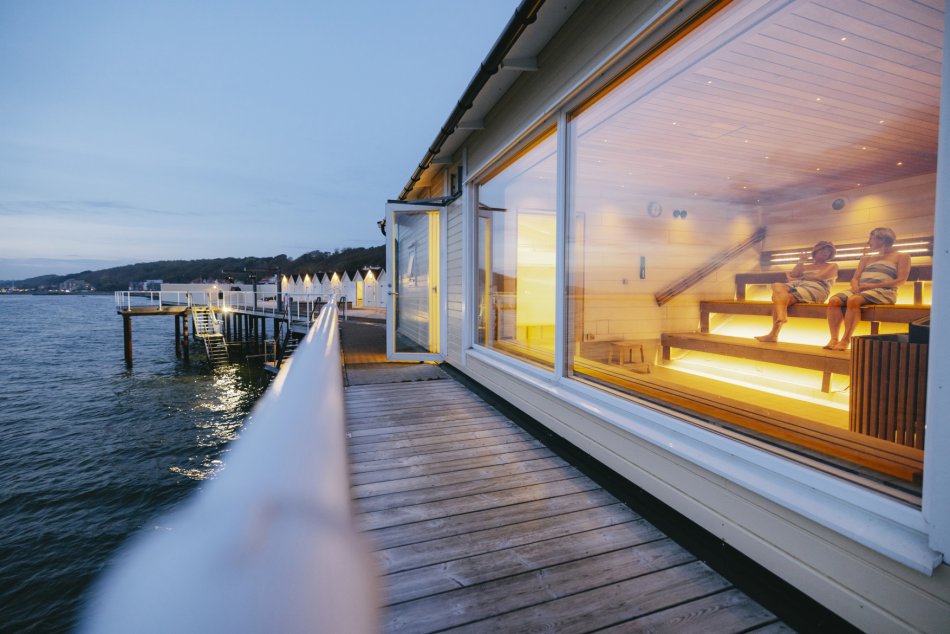 Brygga och stort fönster vid bastu med två kvinnor i randiga handdukar