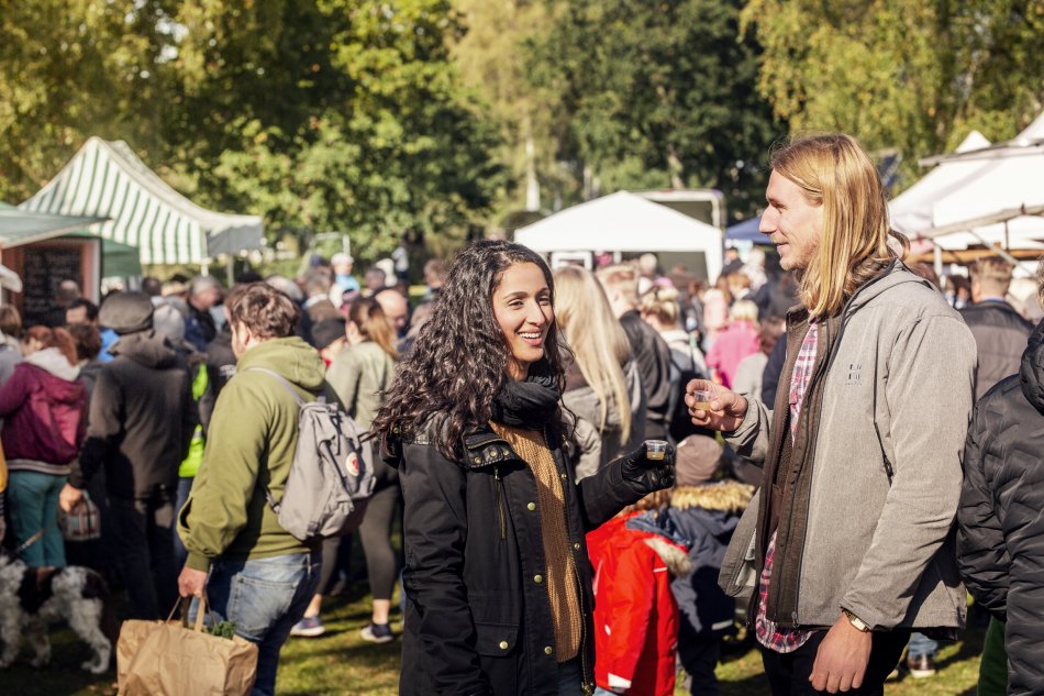 Ett par står i förgrunden till en skördemarknad