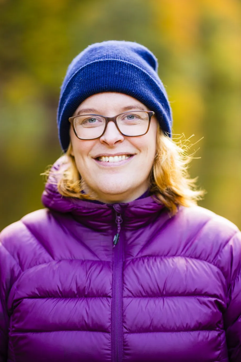 Projektledare Maria Larsson i blå mössa, glasögon och lila tunn dunjacka