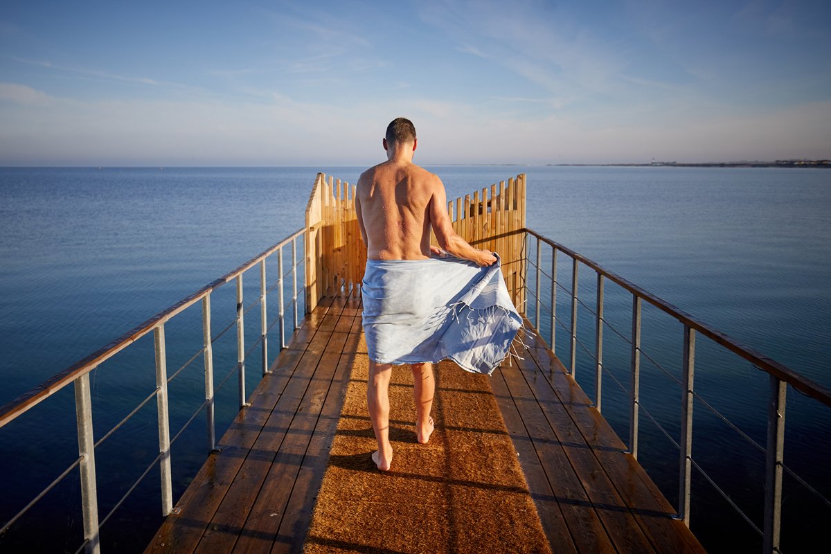 En man är på väg för ett kallbad med en handduk runt höften. Foto.