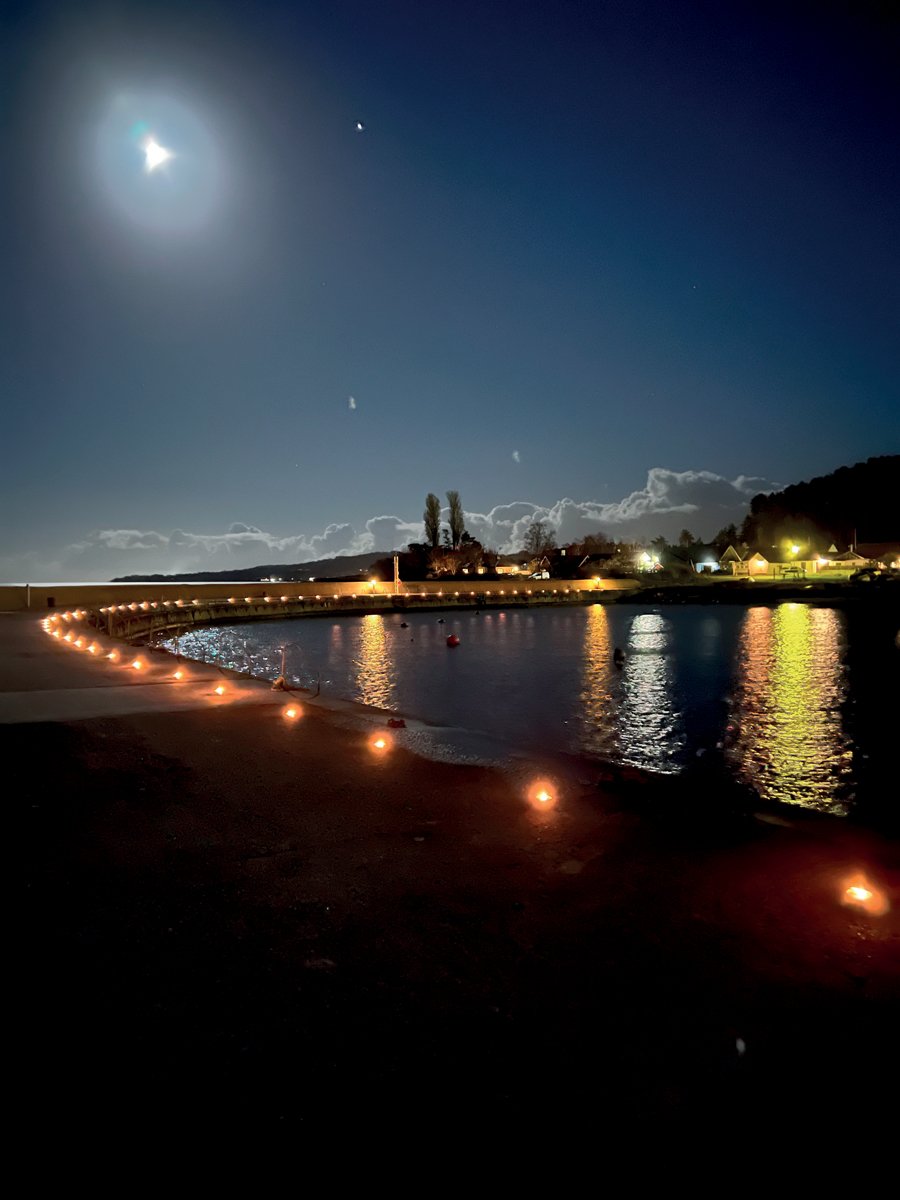 Ljus från både måne och lampor vid en hamn. Foto.